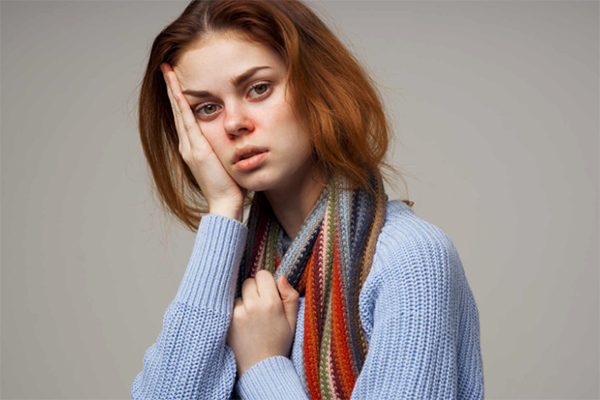 Young Woman in Blue Sweater with Head in Hands