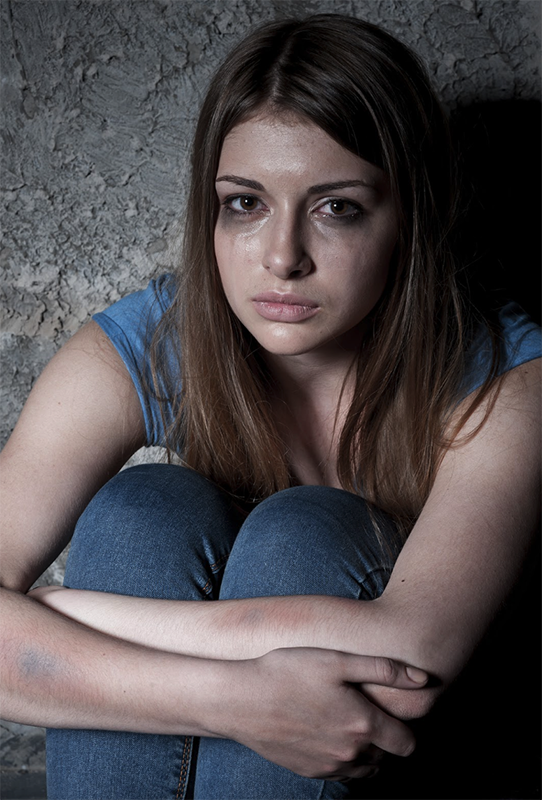 Young Woman with Bruises Sobbing, Sitting Against Wall