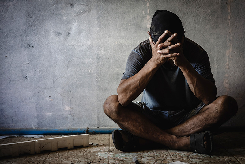 Depressed man sitting by concrete wall