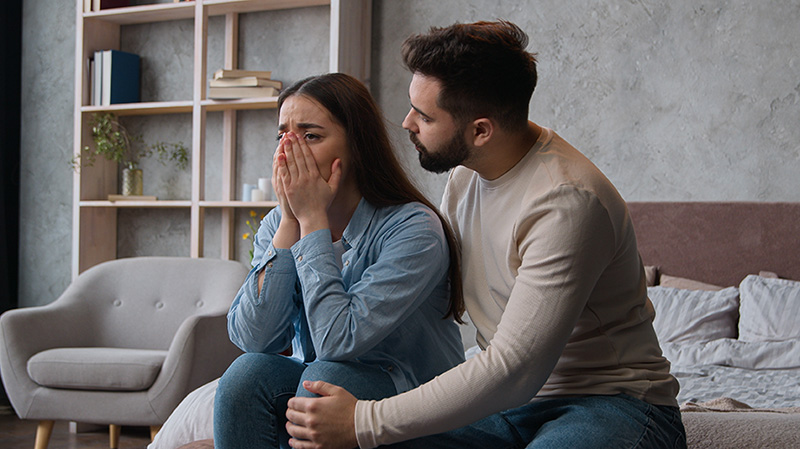 Woman cries as couple argues at home over substance use