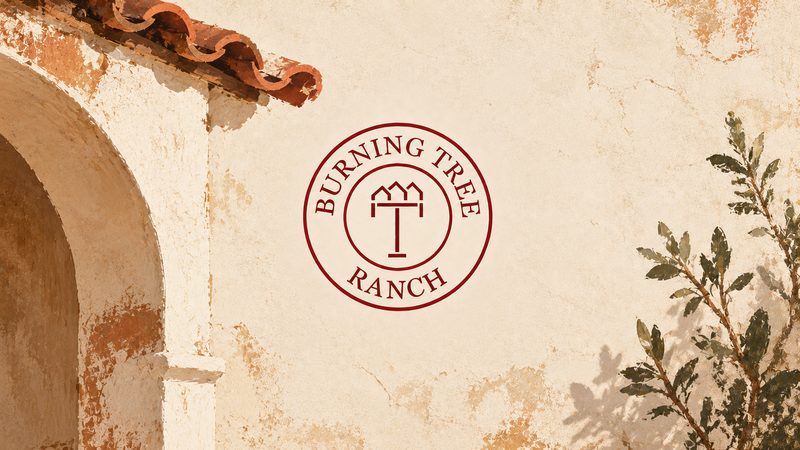 Burning Tree Ranch emblem on a weathered stucco wall between a tiled arch and an olive branch